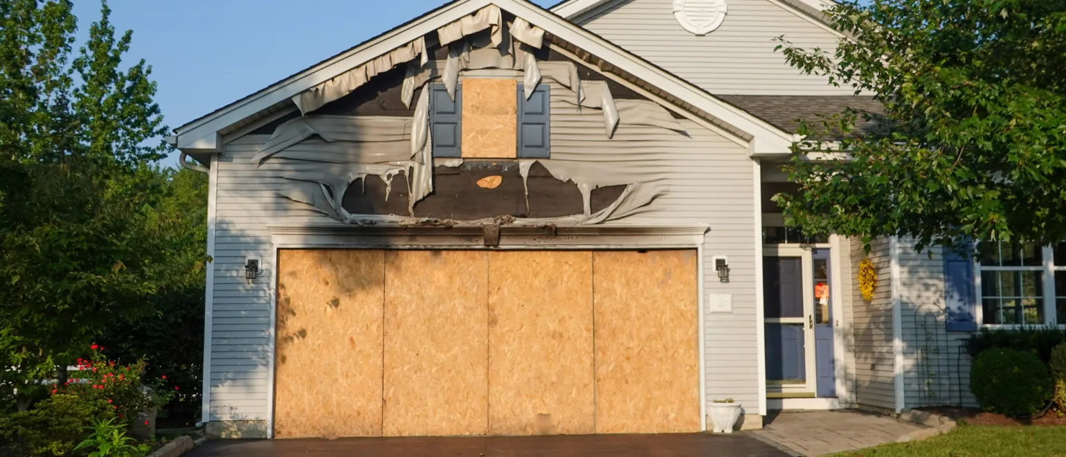 Los Angeles fire damage restoration project showing burned garage exterior, boarded opening, damaged siding, and home rebuild preparation after fire